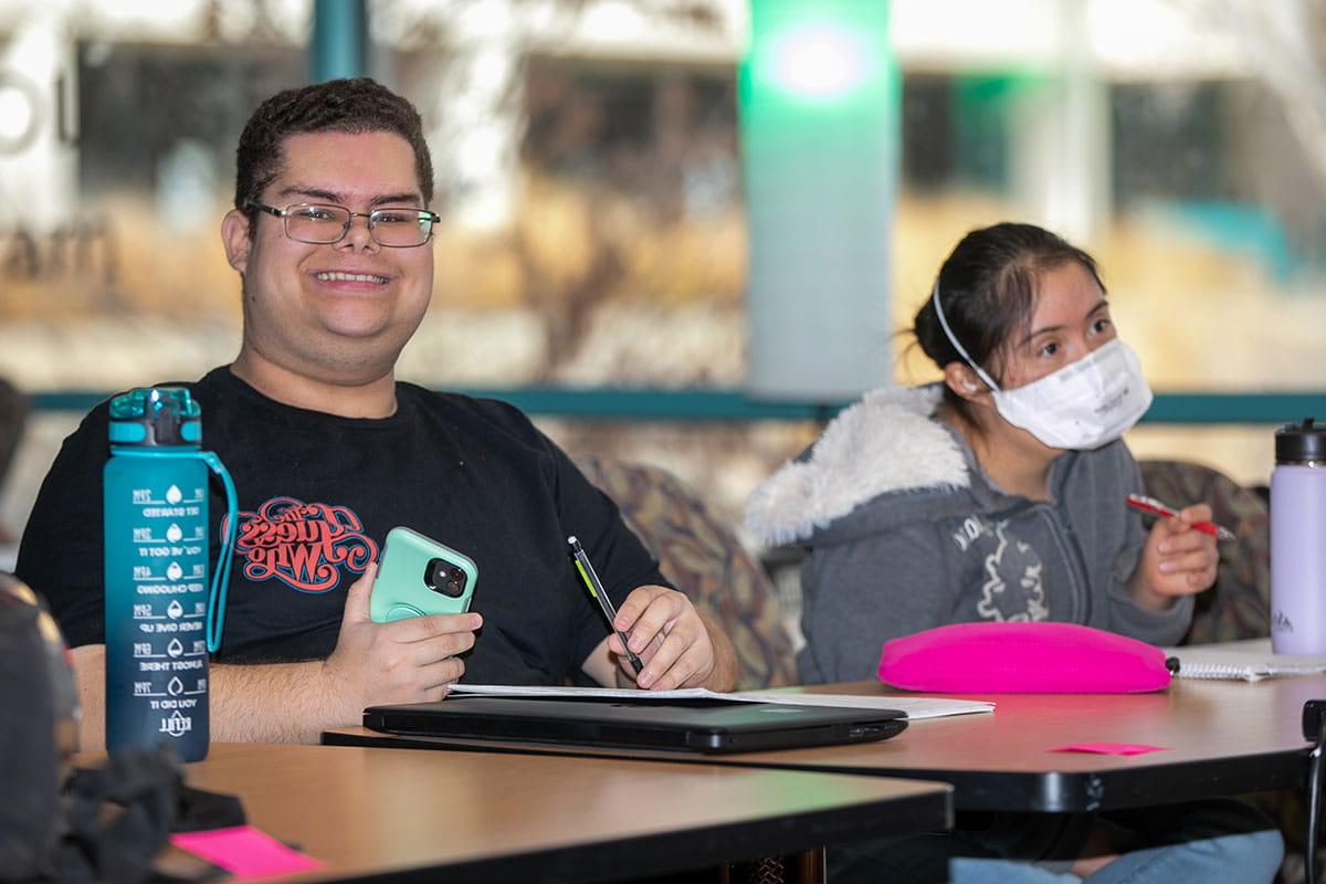 Two San Juan College CLEAR program students taking notes in class